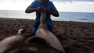 Lucky guy has a sexy lady massaging his feet on the beach