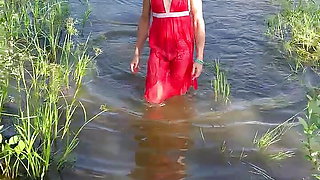 Swimming in lake in coral color summer dress and white sneakers. Wet dress. Wetlook transgirl